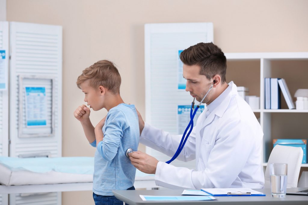 Krztusiec - pediatra osłuchujący kaszlącego chłopca.